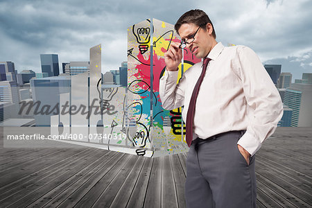 Thinking businessman touching his glasses against cityscape under cloudy sky