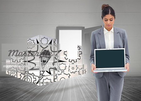 Businesswoman looking at laptop in her hands against open door on white wall