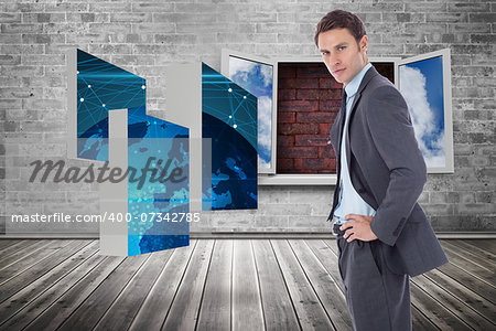 Serious businessman with hands on hips against window frame on red brick wall