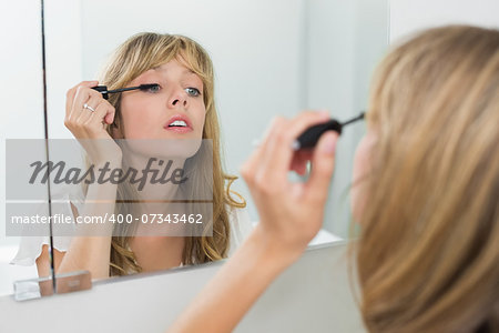 Close-up of a beautiful young woman applying mascara in the bathroom at home