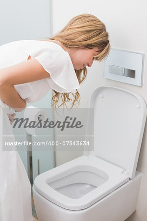 Young woman with stomach sickness about to vomit into a toilet