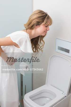 Young woman with stomach sickness about to vomit into a toilet