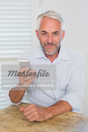 Portrait of a relaxed mature man text messaging at home