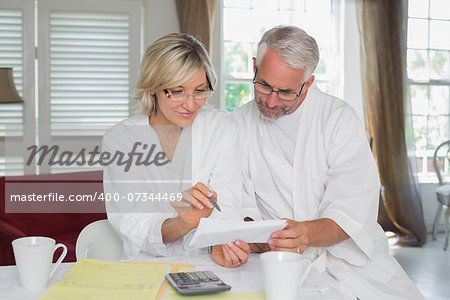 Casual mature couple sitting with home bills and calculator at table