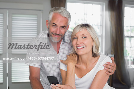 Portrait of a happy mature couple reading text message at home