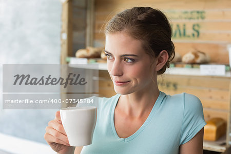 Thoughtful young woman drinking coffee in the coffee shop