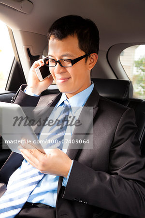 businessman working with tablet and smart phone in the car