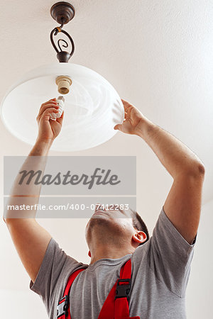 Electrician finished mounting ceiling lamp - installing a fluorescent lightbulb