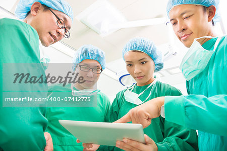 The surgeons useing  tablet  to discuss operating procedure