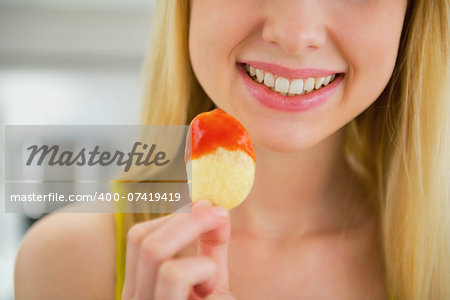 Closeup on young woman eating chips