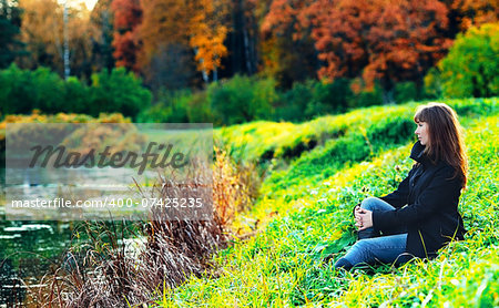 beautiful girl sitting on a shore in autumn forest