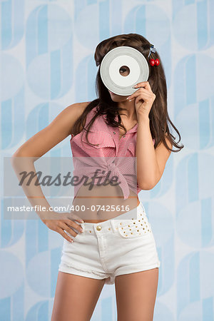 portrait of sexy funny pin-up girl with sexy shorts taking vinyl disc with hand and covering her face portrait of sexy funny pin-up girl with sexy shorts taking vinyl disc with hand and covering her face