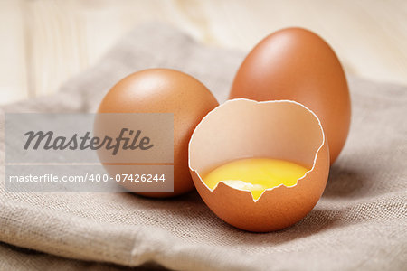 raw chicken eggs one open with yolk, on table