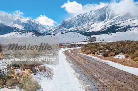 A dirt road wet with melting snow leads across a desert plain toward the Sierra Nevada Mountains near Yosemite National Park.