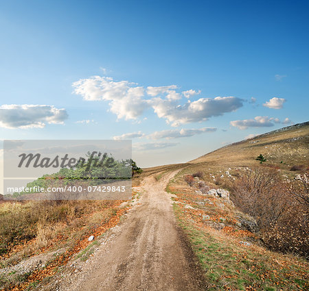 Country road and dry grass on the autumn hill