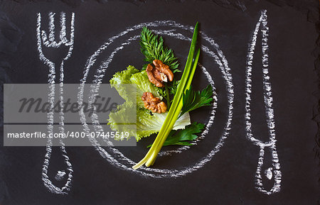 Healthy food concept. Fresh organic green salad on a chalk painted plate.