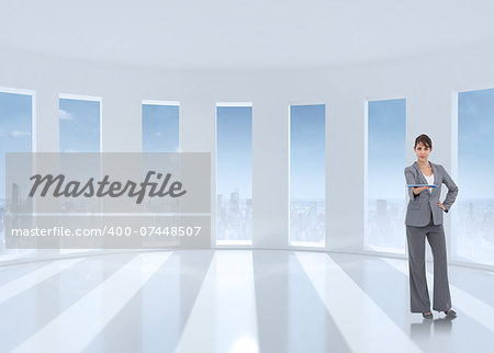 Attractive businesswoman holding tablet pc against bright white room with windows