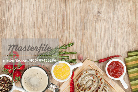 Grilled sausages with ketchup, mustard and mug of beer. Over wooden table background with copy space