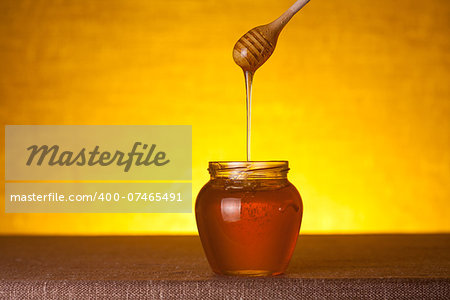 Honey jar with wooden dipper, studio shot