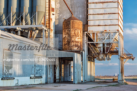 old grain elevator with pipes, ducts, ladders and chutes, a distant rural landscape of northern Colorado