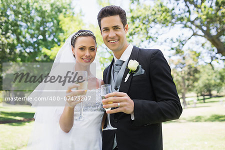 Portrait of newlywed couple toasting champagne in park