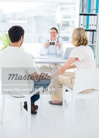 Expectant couple consulting female doctor in clinic