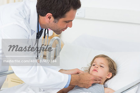 Male doctor checking thyroid glands of sick girl in hospital ward