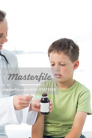 Female doctor giving little boy syrup in hospital