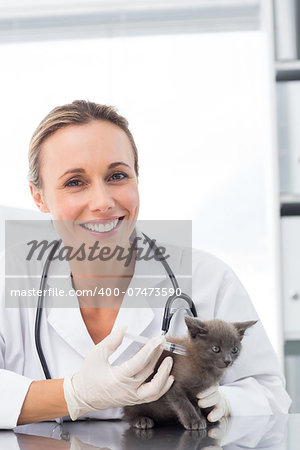 Portrait of smiling female vet injecting a kitten in clinic