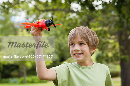 Excited young boy playing with a toy plane at the park