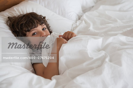 High angle portrait of a young boy resting in bed at home