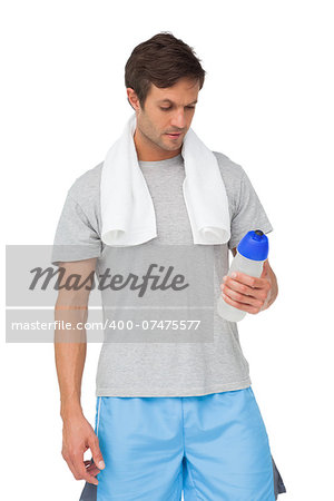 Fit young man with water bottle and towel standing over white background