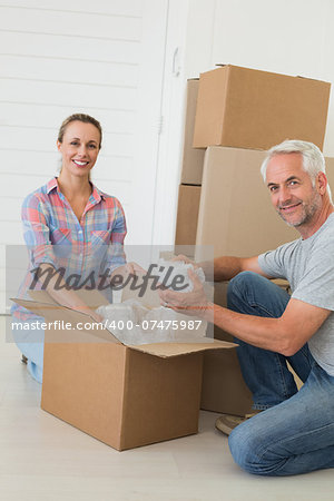 Happy couple unpacking cardboard moving boxes in their new home