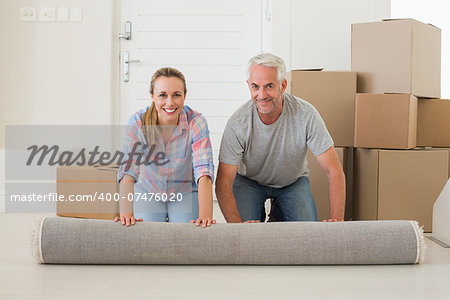 Happy couple rolling out new rug in their new home