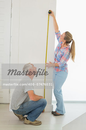 Happy couple making some measurements together in their new home