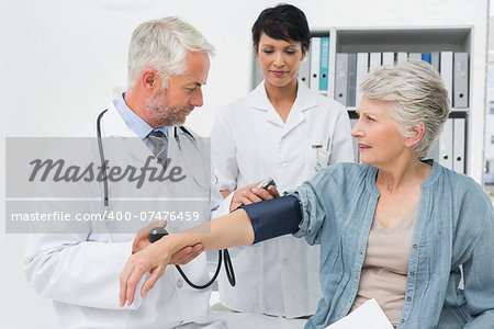 Male doctor measuring blood pressure of a senior patient in the medical office