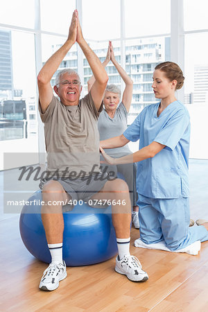 Female therapist assisting senior couple with exercises in the medical office