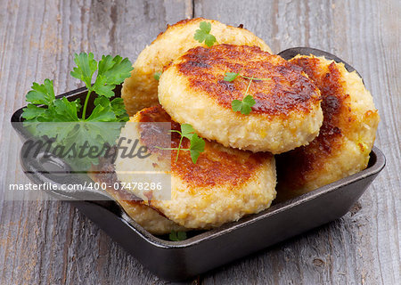 Delicious Chicken Meat Cutlets in Black Saucepan with Parsley isolated on Rustic Wooden background