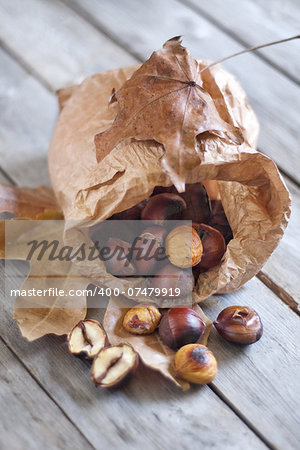 Roasted chestnut in a papper bag on old wooden table.