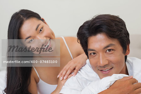 Happy couple lying on bed together at home in bedroom
