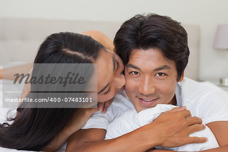 Happy couple lying on bed together at home in bedroom