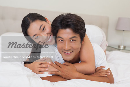 Happy couple lying on bed together at home in bedroom