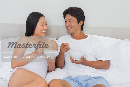 Happy couple having breakfast in bed at home in bedroom