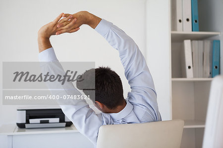 Casual businessman stretching in swivel chair in his office