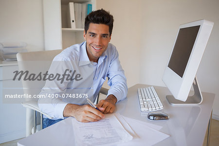 Casual businessman sitting at desk writing in his office