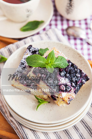 Portion of fresh homemade blueberry cake and cup of tea on the background