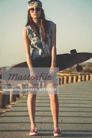 Beautiful and fashion young woman posing with a skateboard