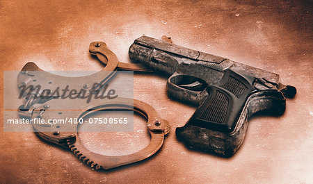 Gun and handcuffs on table. Photo in old color image style