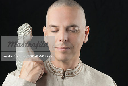 Close-up of a buddhist meditating, holding a stone buddha statue.