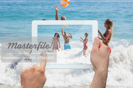 Hand holding tablet pc showing young friends having fun at the beach